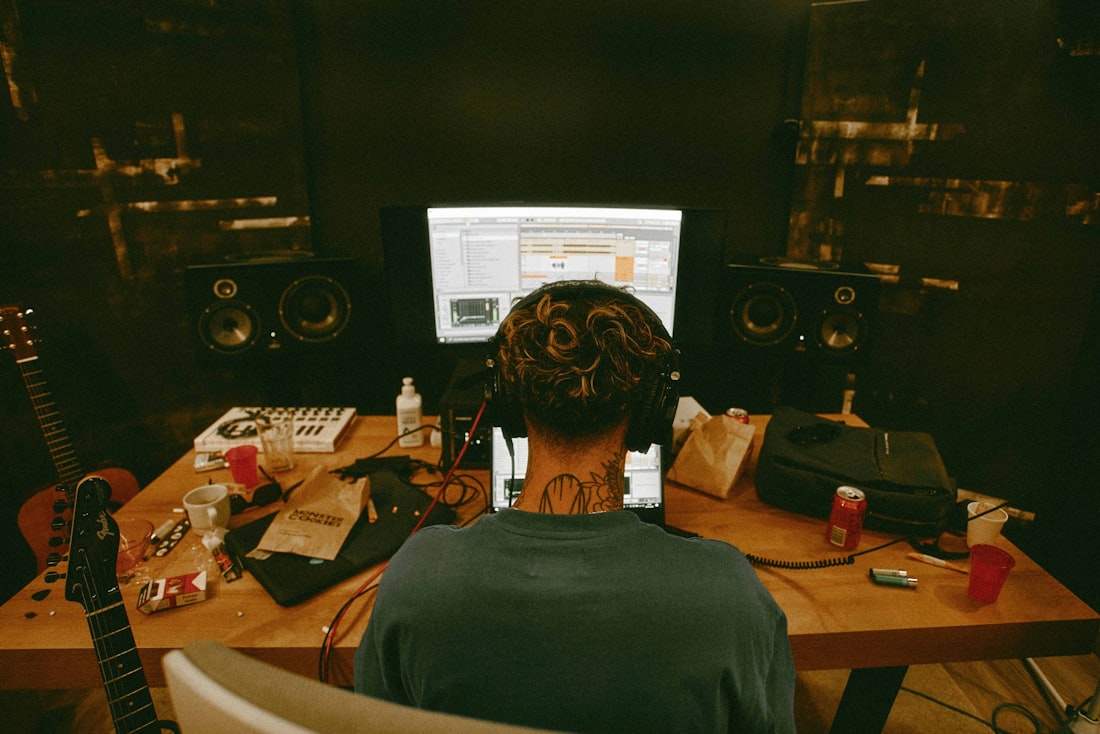 A producer working at a cluttered studio desk, seen from behind