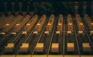 Close-up of mixing console faders in warm light